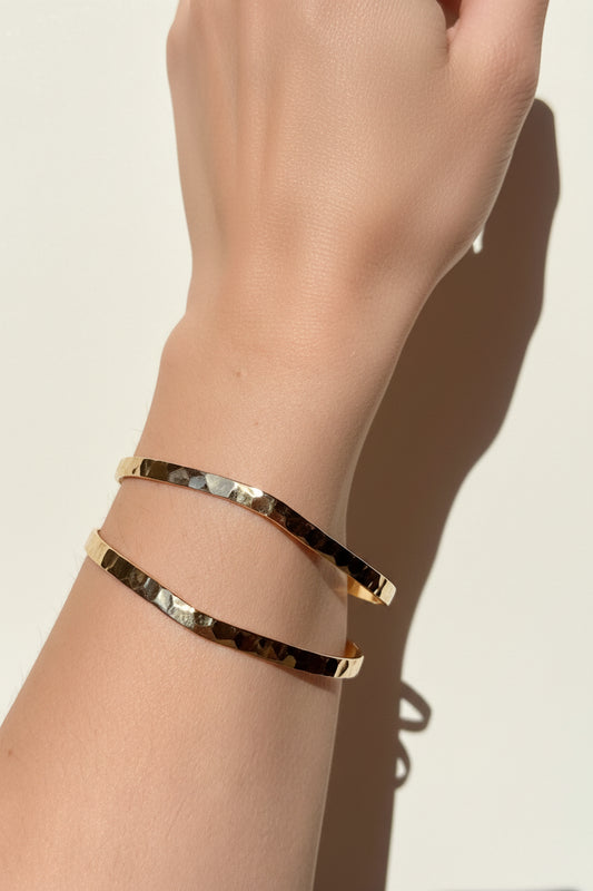 La Pulsera Esclava Doble Martillada Bañada en Oro 18K – Golden Flow es una pieza moderna y sofisticada