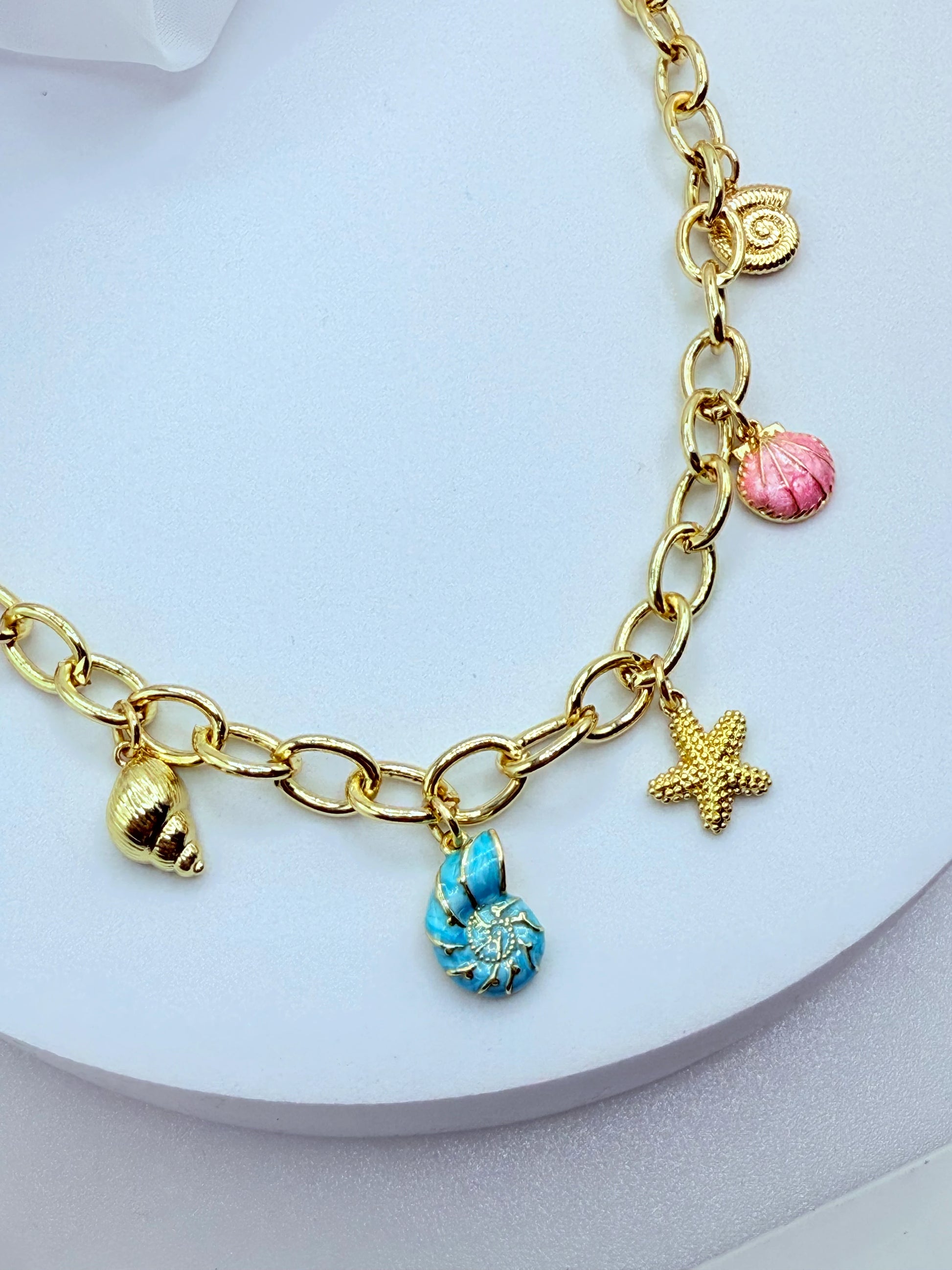 Collar con dijes marinos y cadena de eslabones bañado en oro. Perfecto para looks coloridos y para regalar en ocasiones especiales