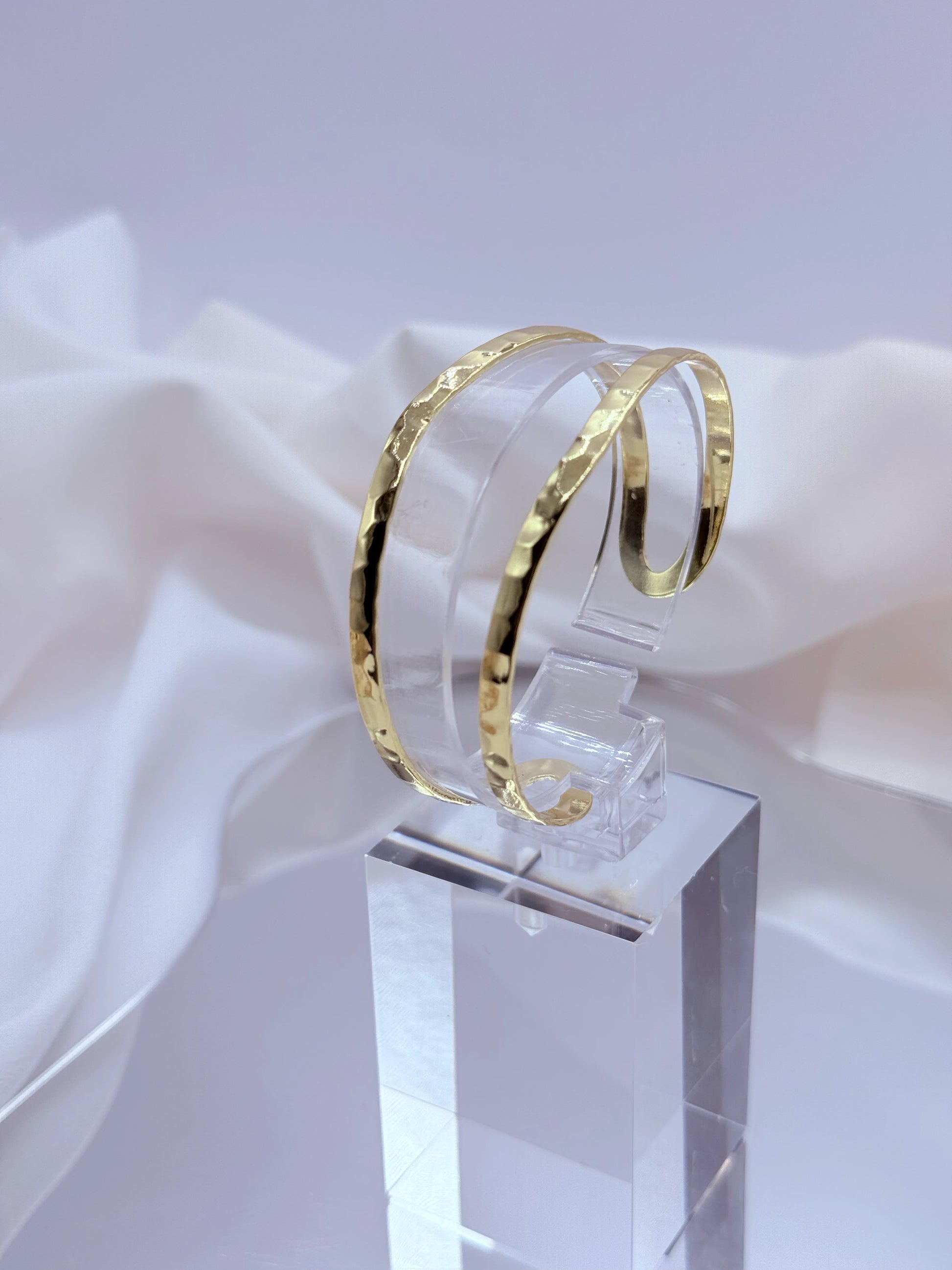 La Pulsera Esclava Doble Martillada Bañada en Oro 18K – Golden Flow es una pieza moderna y sofisticada