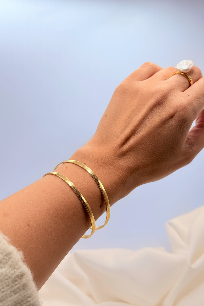 La Pulsera Esclava Doble Martillada Bañada en Oro 18K – Golden Flow es una pieza moderna y sofisticada