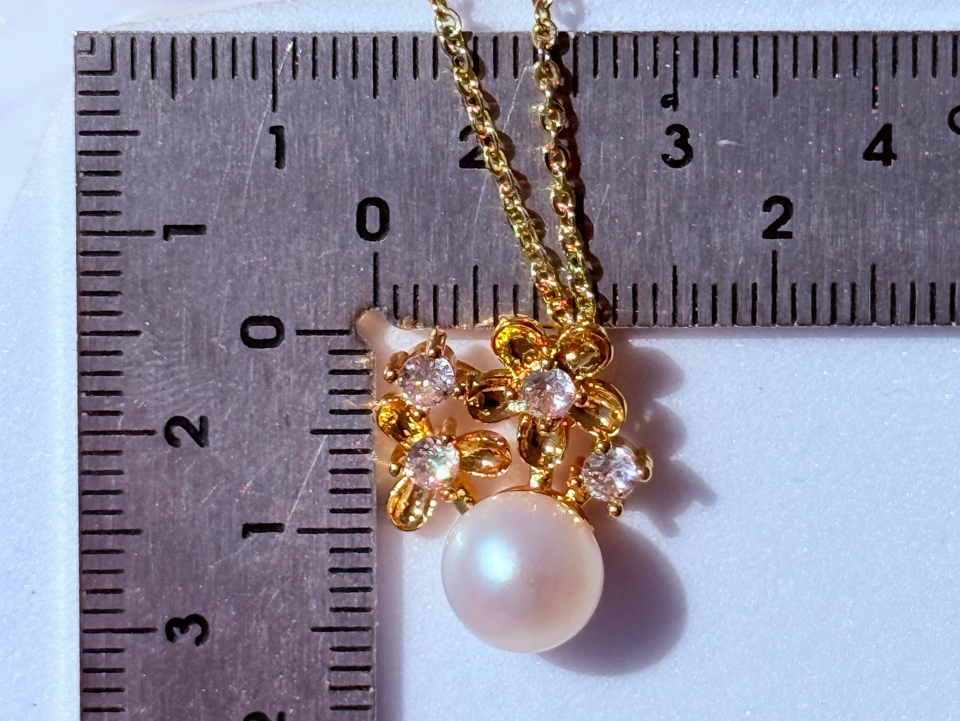 detalle collar con perla natural y flores de circones baño oro 18k