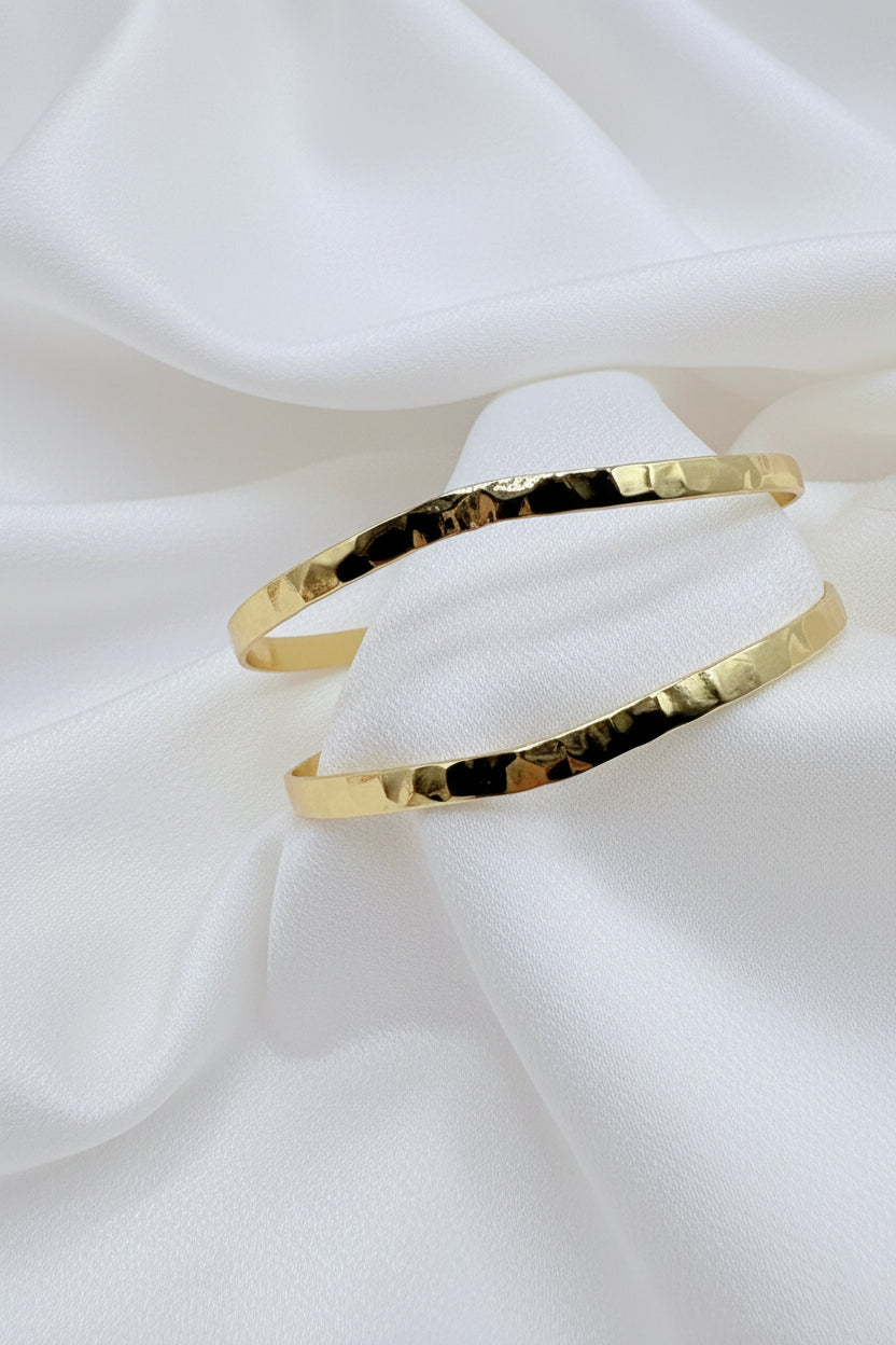 La Pulsera Esclava Doble Martillada Bañada en Oro 18K – Golden Flow es una pieza moderna y sofisticada