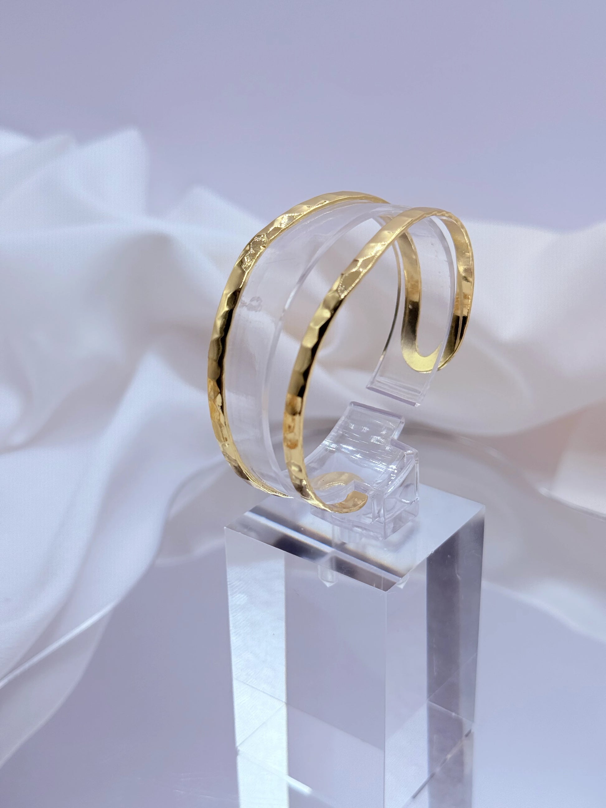 La Pulsera Esclava Doble Martillada Bañada en Oro 18K – Golden Flow es una pieza moderna y sofisticada