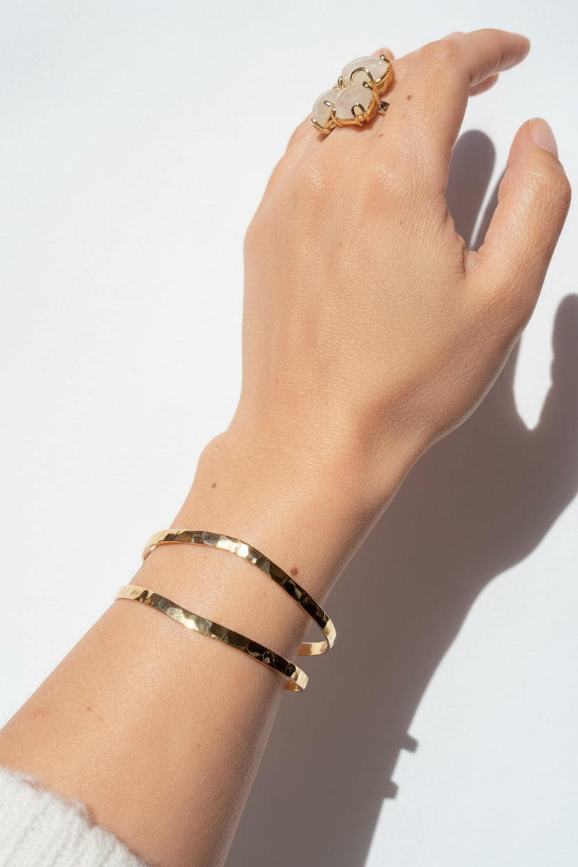 La Pulsera Esclava Doble Martillada Bañada en Oro 18K – Golden Flow es una pieza moderna y sofisticada